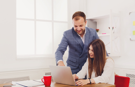 Businessman supervising his female assistant's work on laptop computer